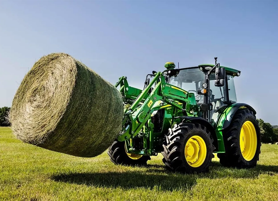 John Deere 5130M Compact Tractor Moving A Round Hay Bale